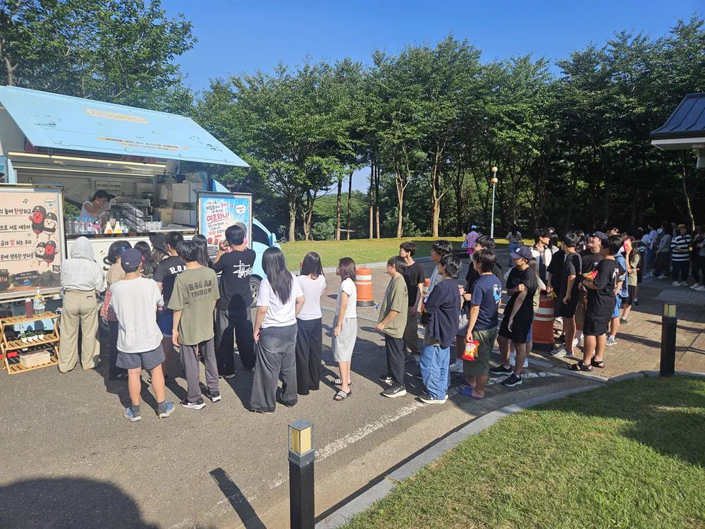 야외 행사장에서 푸드트럭 앞에 줄을 선 방문객