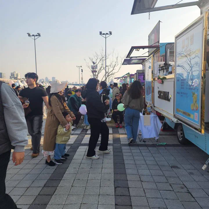여러 대의 푸드트럭이 줄지어 선 행사장과 방문객들